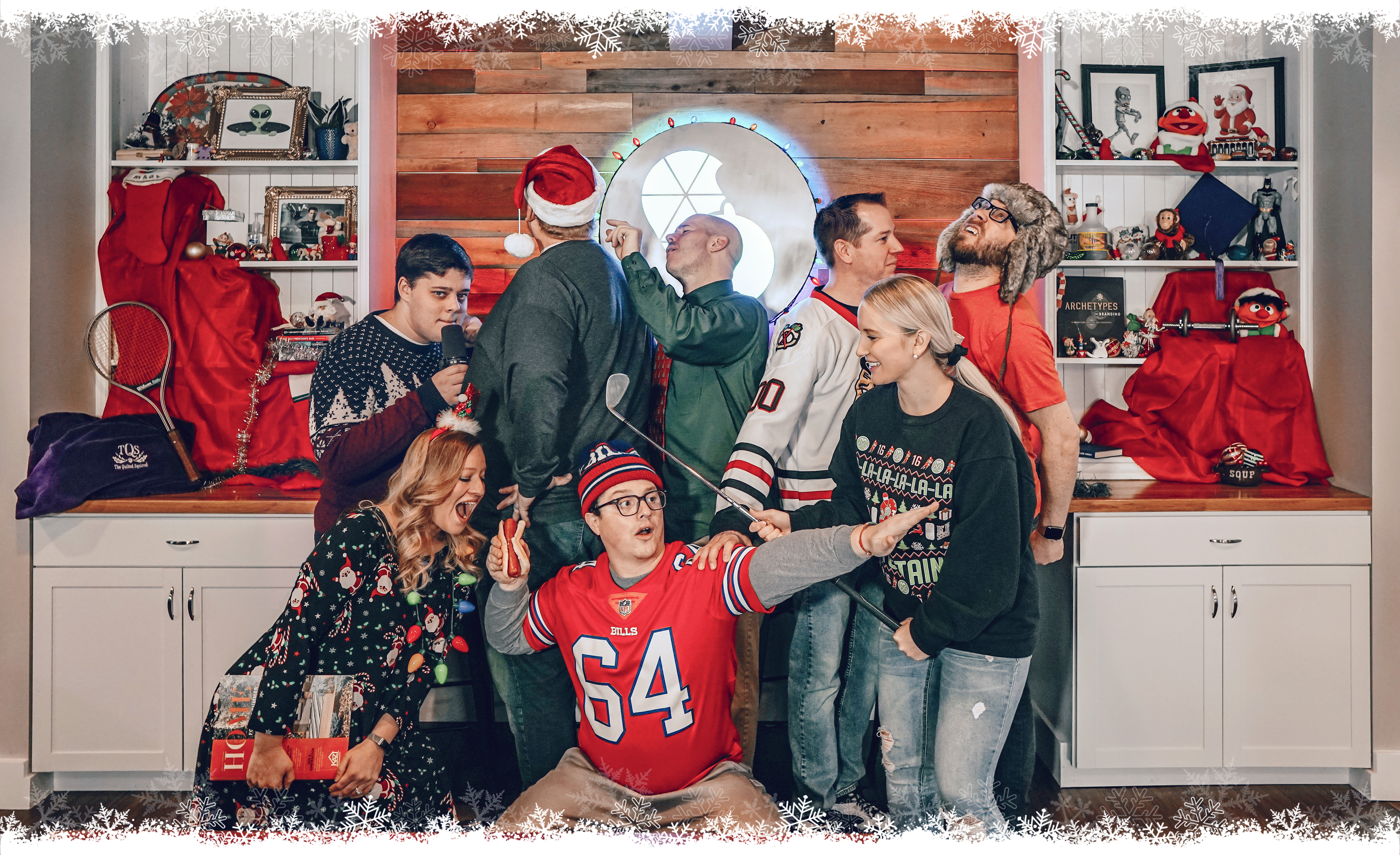 TQS Holiday Photo Hunt! Eight human employees stand in various silly positions among a holiday-themed backdrop that features a smattering of holiday decorations and other random objects