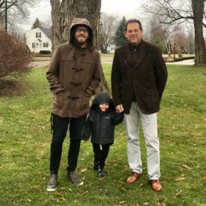 Happy Father's Day: Two men, a father and son, stand on either side of a small boy on a rainy day. 