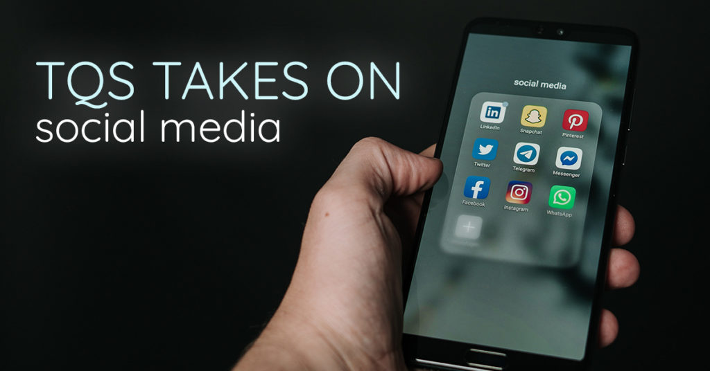 TQS takes on social media! A hand holds a smartphone that is loaded with apps.